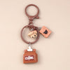A brown leather keychain featuring a coffee bean charm and a small coffee tin.