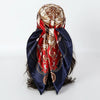A dark blue satin silk scarf tied around a head, featuring intricate gold and red embroidery.