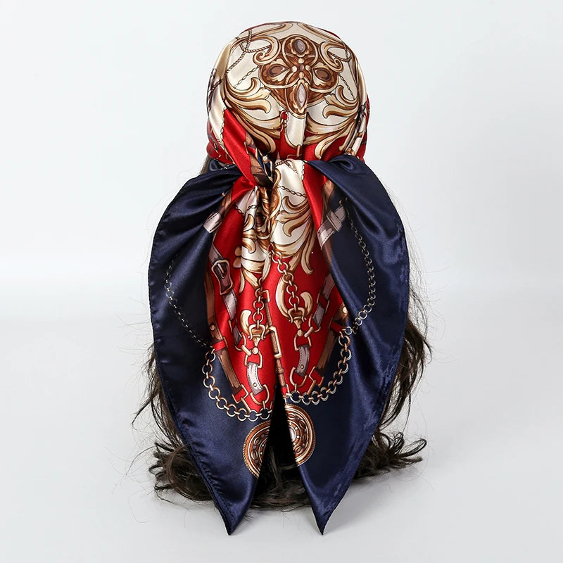 A dark blue satin silk scarf tied around a head, featuring intricate gold and red embroidery.