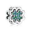 A silver family tree charm featuring five green and blue gemstones set in a floral design.