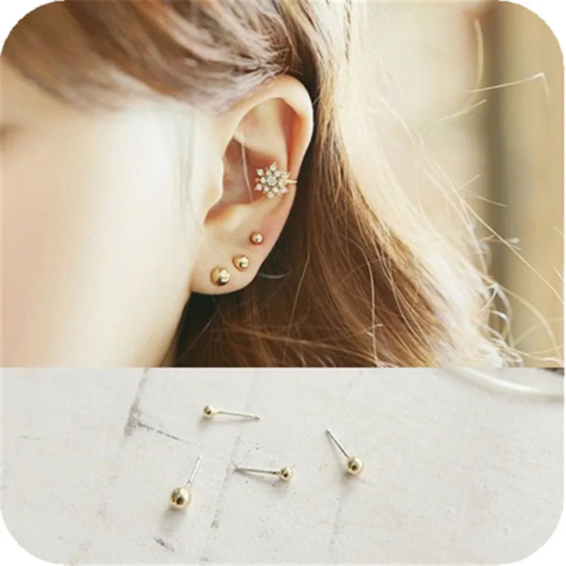 A close-up of a woman's ear adorned with a cluster of gold-toned round stud earrings.