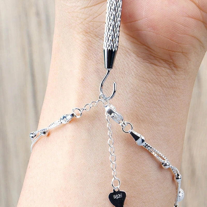 A close-up of a hand wearing a silver precision jewelry tool kit for clasps and closures.