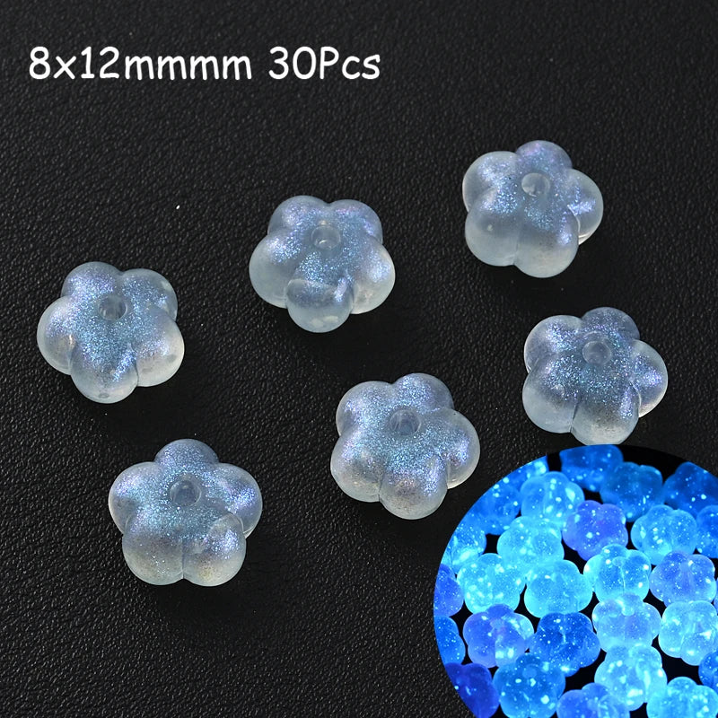 30 pieces of luminous glow-in-the-dark acrylic beads in a light blue color scattered on a black surface