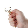 A hand is holding a gold-colored metal glove clip holder with a curved jaw.