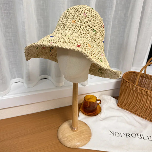 A hand-crocheted Panama straw sun hat displayed on a mannequin against a white curtain.