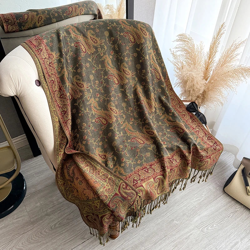 A brown and gold bohemian paisley tassel shawl draped over a light-colored chair.