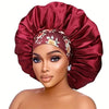 A model is wearing a deep red satin sleep bonnet with an elastic band on her head.