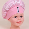Pink satin sleep cap for kids with a black letter I embroidered on the front