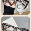 A pair of tortoiseshell cat eye sunglasses with light green accents are shown on a hand against a white background.