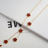 Pulsera de flor de planta de acero inoxidable chapada en oro con pequeños acentos rojos, mostrada sobre fondo blanco.