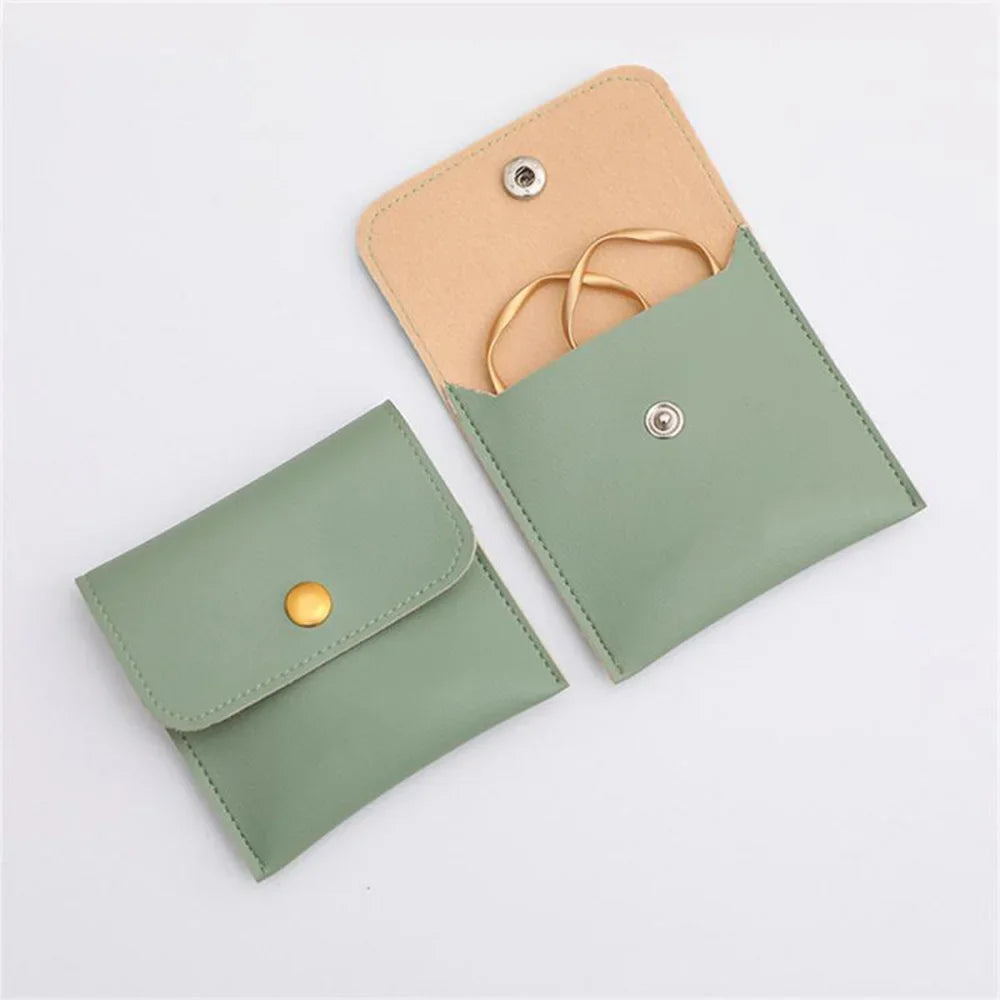 A light olive green PU leather jewelry pouch with a snap button closure and a gold-colored cord.