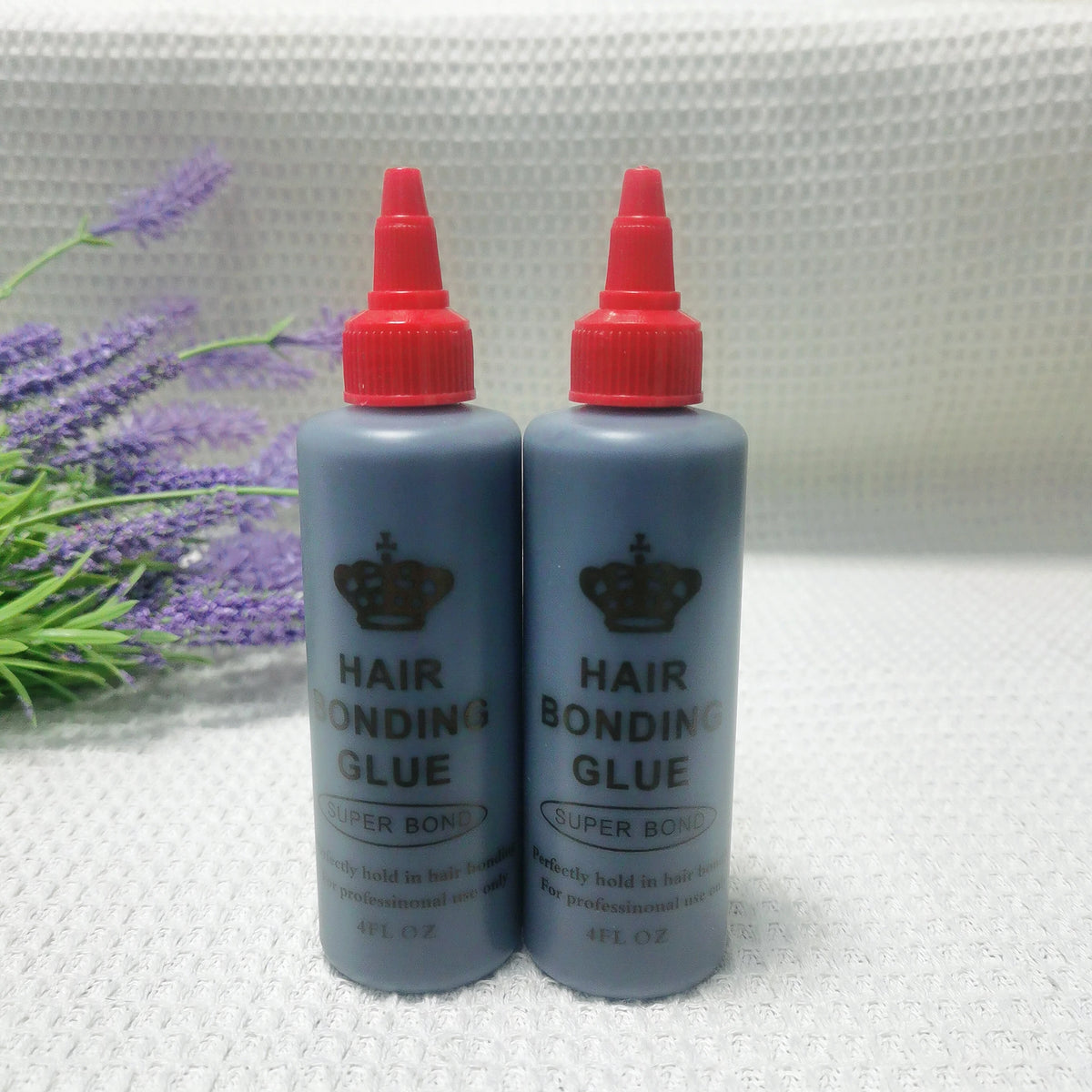 Two bottles of professional hair bonding glue with red caps and gray liquid are shown on a white surface.