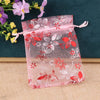 Pink sheer satin drawstring pouch with floral patterns and red accents for jewelry gifts