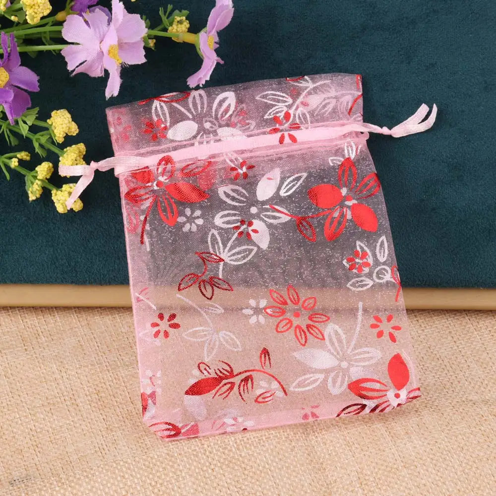 Pink sheer satin drawstring pouch with floral patterns and red accents for jewelry gifts