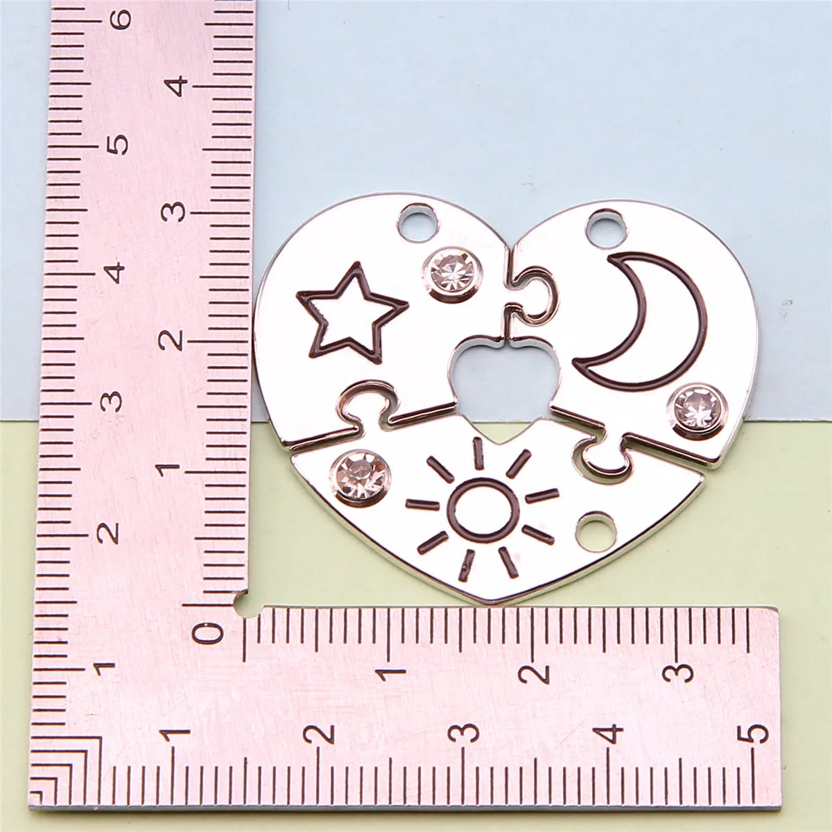 Collar de amistad multi-set con colgantes en forma de corazón con estrellas, lunas y soles, medido contra una regla.