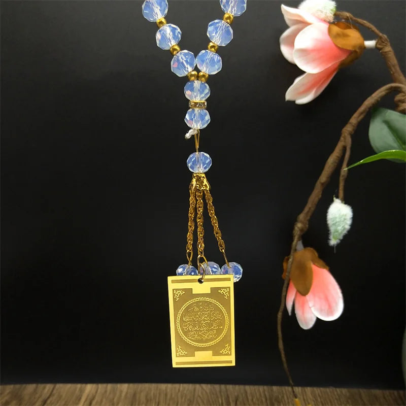 A gold-toned stainless steel pendant featuring blue glass beads and a Quran Arabic design.