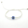 A white beaded bracelet with a blue and black evil eye charm.