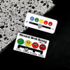 A white pin featuring various facial expressions like happy, sad, and angry faces, used for mood expression on clothing.