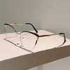 Un par de gafas de ordenador con montura metálica dorada y lentes transparentes sobre una superficie blanca.
