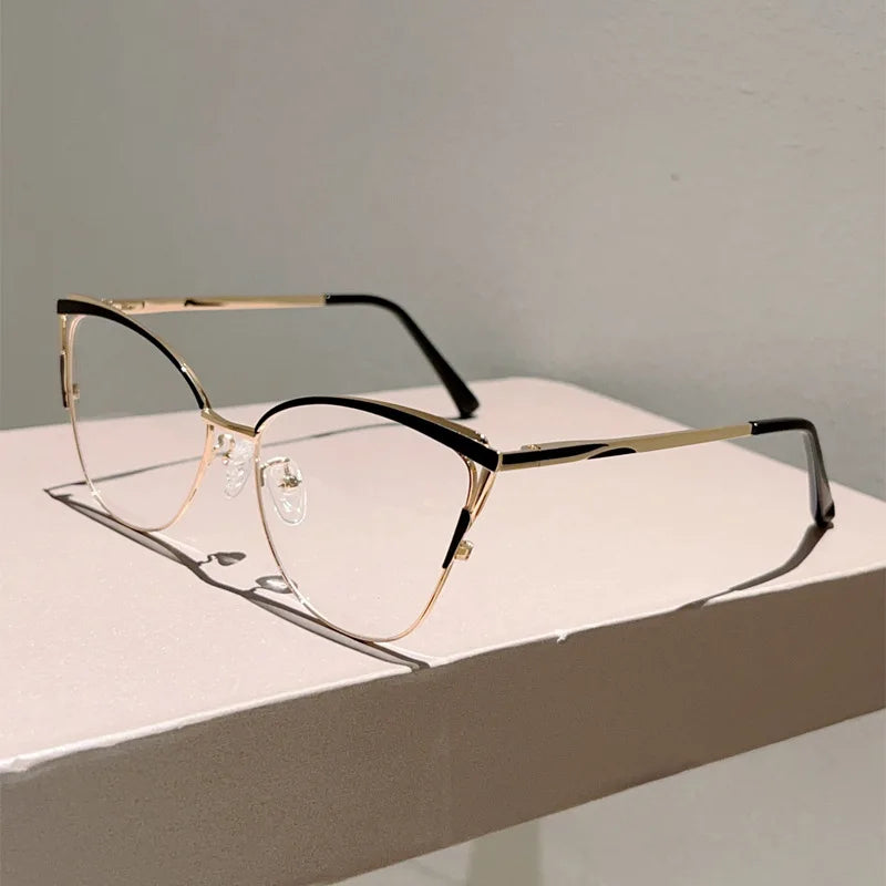 Un par de gafas de ordenador con montura metálica dorada y lentes transparentes sobre una superficie blanca.