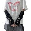 A person wearing a white t-shirt and gray skirt, featuring black knitted arm warmers with star details.
