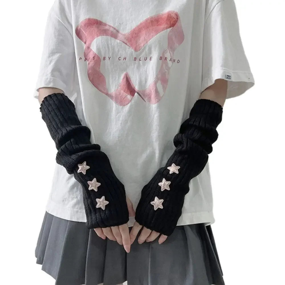 A person wearing a white t-shirt and gray skirt, featuring black knitted arm warmers with star details.