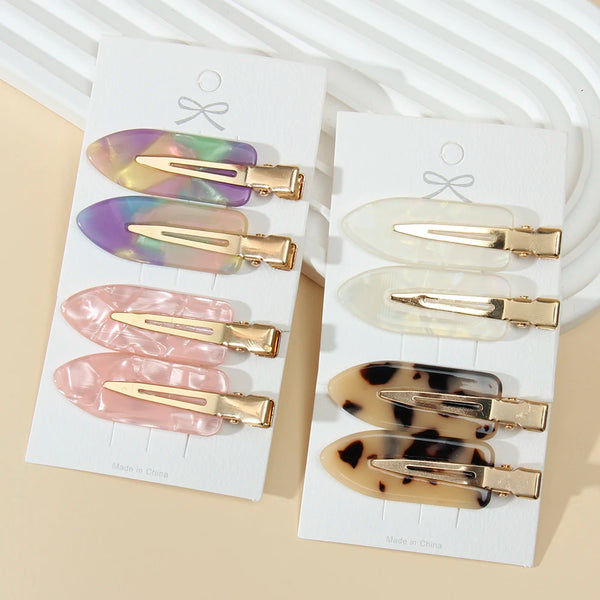 A set of five gold-toned leopard print seamless hair clips displayed on white cards.