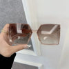 A pair of rose gold mirror square sunglasses held by a hand against a white background.