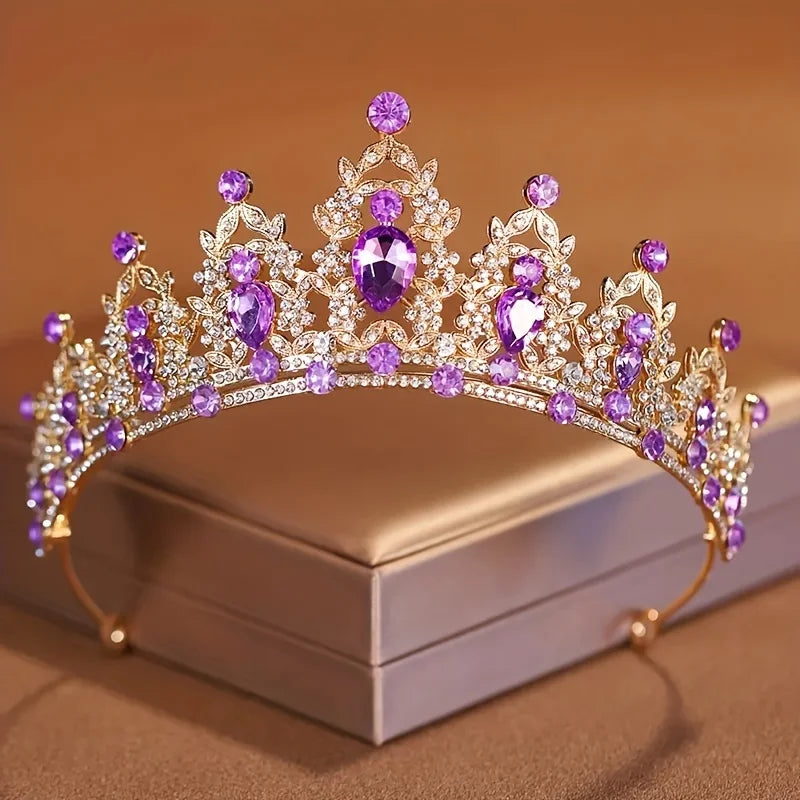 Diadema de cristal brillante con piedras moradas y claras, mostrada sobre una caja neutra.