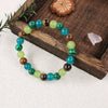 A bracelet made of natural stone beads in shades of green and blue is displayed on a wooden surface.