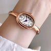 A close-up of a rose gold Zido quartz analog watch with an oval face worn on a wrist.