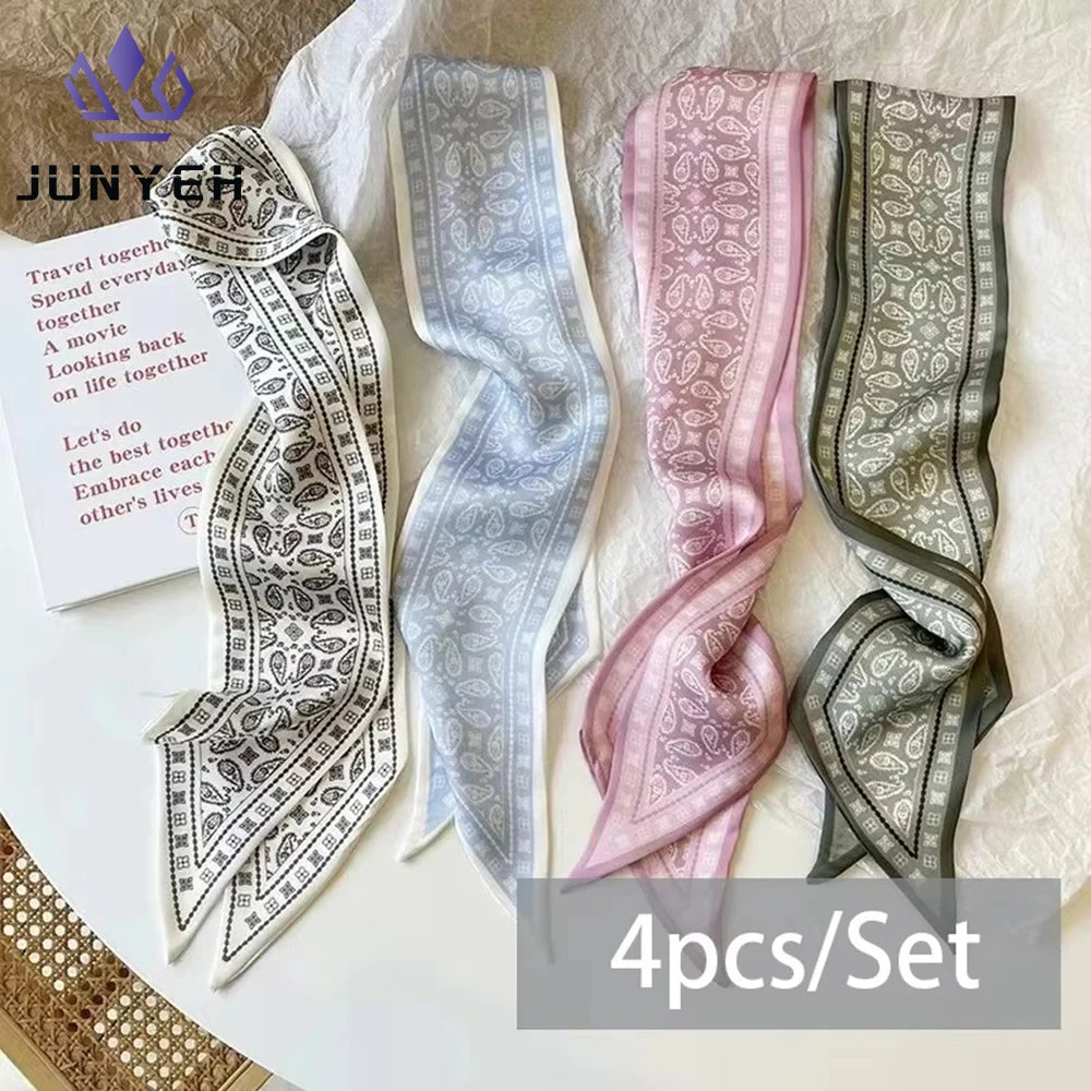 A set of four silk satin hair and bag accessories in various shades of gray and pink