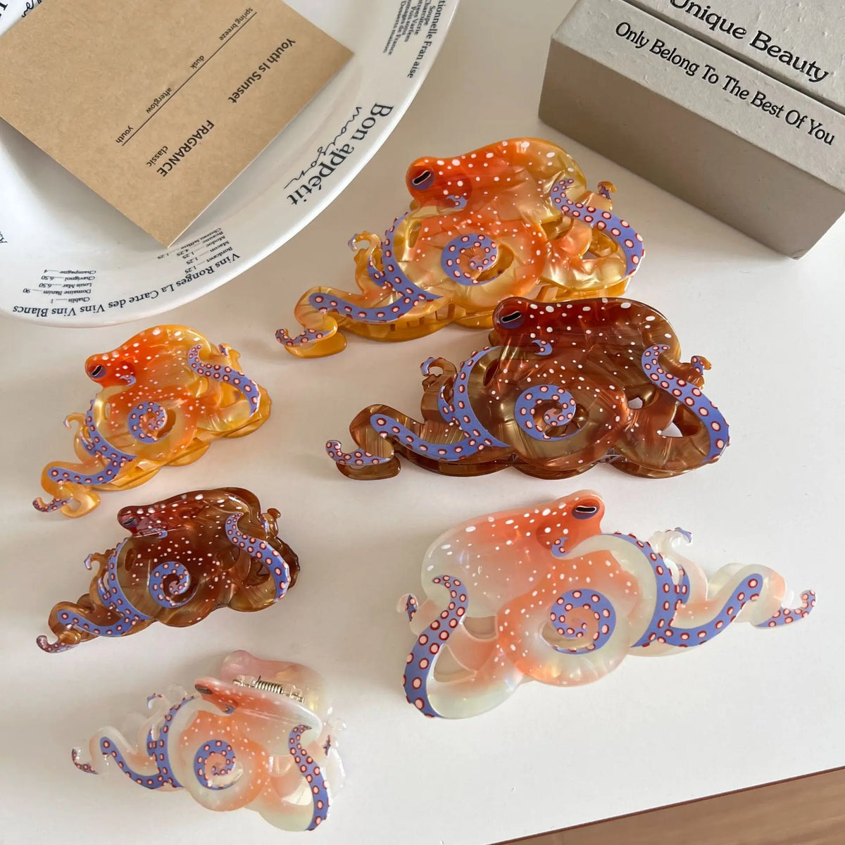 Collection de pinces à cheveux en forme d'œuvres d'art, translucides et colorées (orange, violet, bleu).
