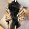 Schwarze und beige karierte Pashmina-Schal, über einer Oberfläche drapiert.