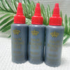 Three bottles of professional hair bonding glue with red caps and gray liquid sitting on a white surface.