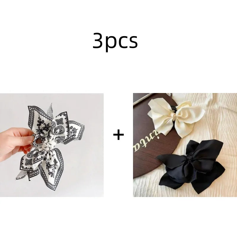 Tres elegantes pinzas para el cabello con patrón de anacardo vintage junto a un lazo negro.