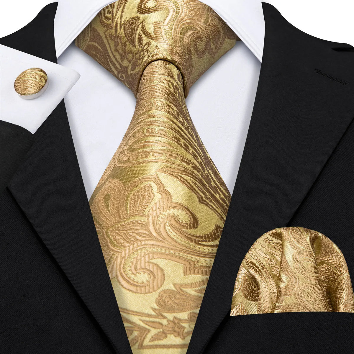 A close-up of a men's silk jacquard tie in gold paisley pattern worn with a black suit jacket and white shirt.