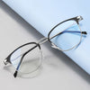A pair of thin, silver-framed eyeglasses with blue accents resting on a light blue surface.
