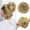 A blonde woman shows off a styled messy bun hairstyle with loose curls and hair pieces.