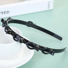 Black multi-layer braided hair headband clip resting on a white saucer.