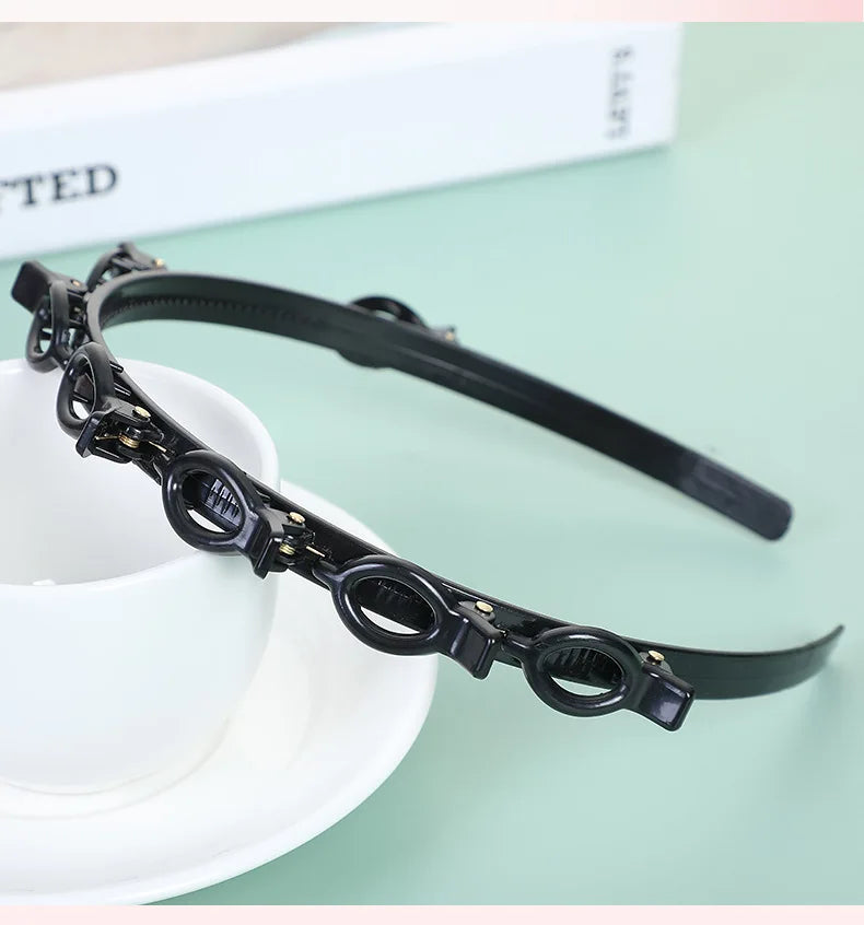 Black multi-layer braided hair headband clip resting on a white saucer.