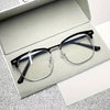 A pair of retro half gold frame anti blue light eyewear resting on a white card inside a gray box.