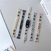 A collection of five diamond four-leaf clover watch straps for a Xiaomi Mi Band displayed on a gray surface.