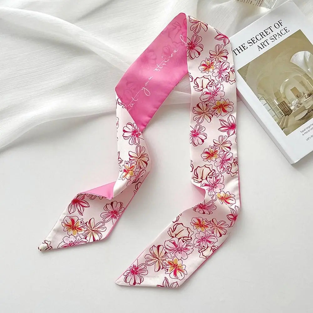 Diadema de flor de seda rosa, pañuelo atado en lazos contra fondo blanco.