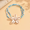 A beaded bracelet featuring white and blue cowrie shells with a floral charm.