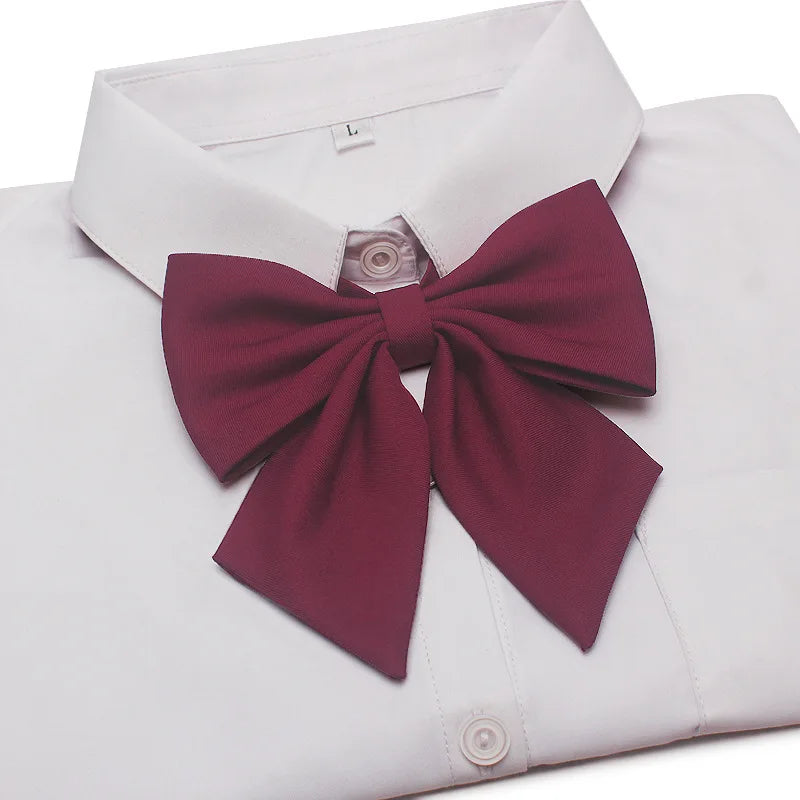A white dress shirt with a maroon butterfly ribbon tie neatly tied at the collar.