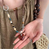 A close-up of a bohemian heart beaded pendant necklace worn by a person, featuring natural wood and stone beads.