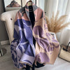 A draped luxury plaid cashmere feel scarf and shawl wrap in shades of mauve, purple, and beige.
