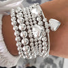 A silver beaded bracelet set featuring round and heart-shaped charms worn on a wrist.