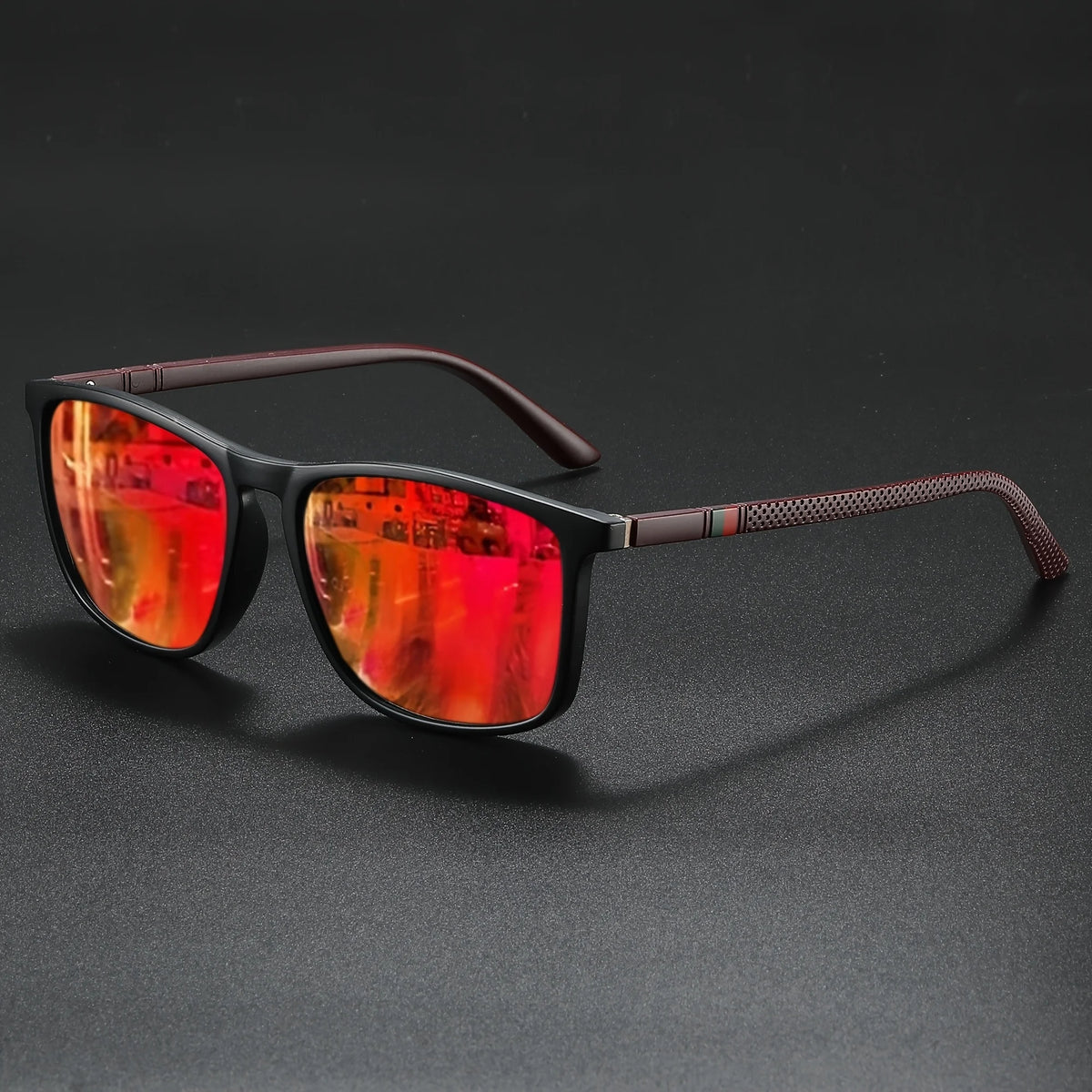 A pair of classic square sunglasses with reddish-orange tinted lenses and dark brown frames resting on a black surface.